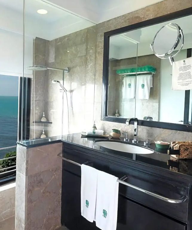Badezimmer mit großen Spiegeln und Meerblick, elegante Dusche und Waschbecken.