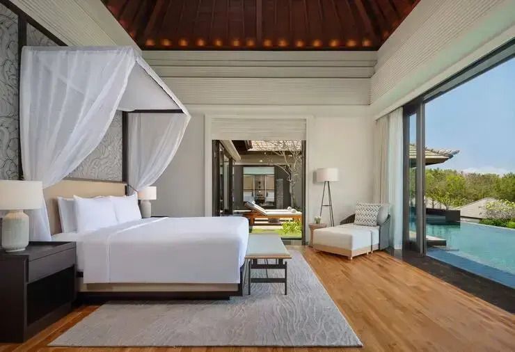 Helles Schlafzimmer in Poolvilla mit Glasschiebetüren zu Terrasse und Pool
