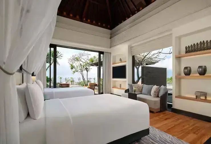 Helles Schlafzimmer mit zwei Betten, Blick auf tropischen Garten und Meer