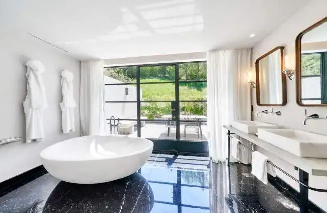 Modernes Badezimmer mit freistehender Badewanne, großem Fenster und Blick ins Grüne