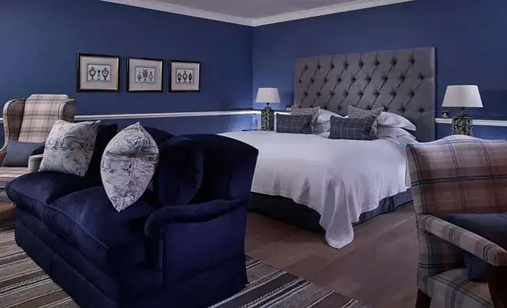 Elegantes Schlafzimmer mit dunkelblauer Wandfarbe und grauem Kopfteil im Croquet Lawn Doppelzimmer.