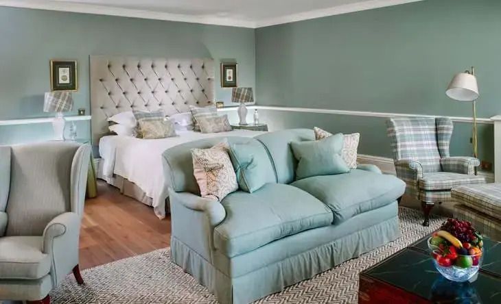 Geräumiges Schlafzimmer mit grünem Kopfteil und gemütlichem Sofa im Croquet Lawn Doppelzimmer.