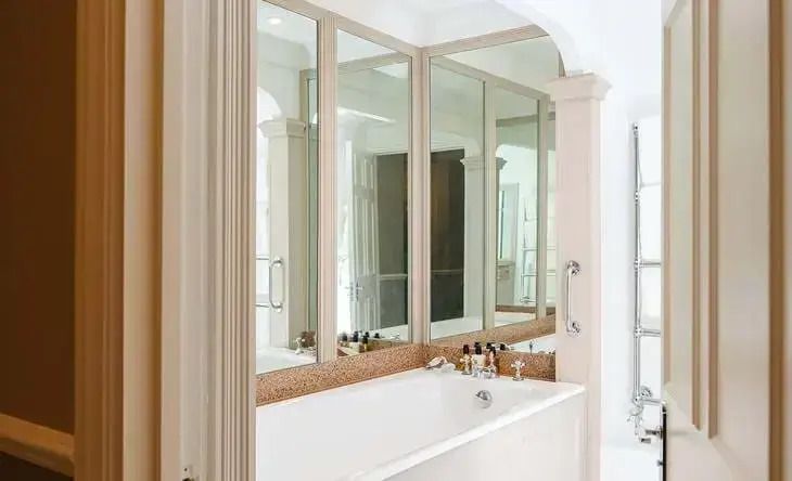 Modernes Badezimmer mit großen Spiegeln und luxuriöser Badewanne im Croquet Lawn Doppelzimmer.