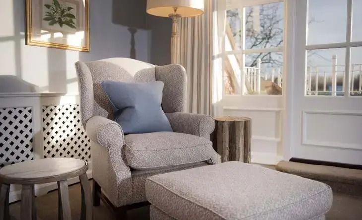 Bequemer Sessel mit Hocker in einer elegant eingerichteten Suite mit Fensterblick.
