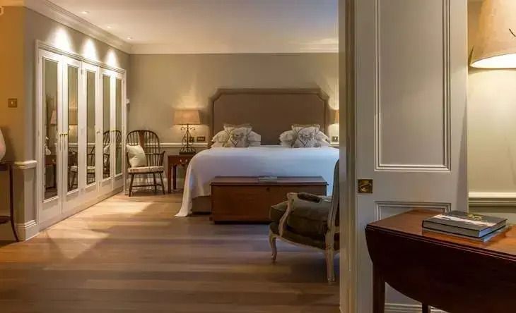 Luxuriöses Schlafzimmer mit großem Doppelbett, Spiegeln und stilvollen Stühlen