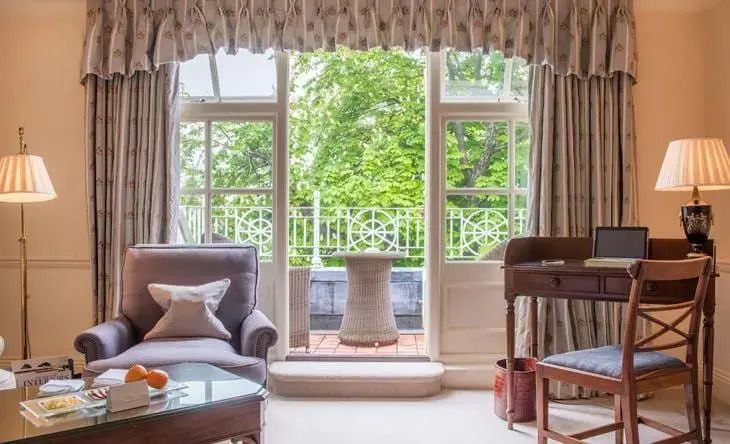 Elegantes Zimmer mit Zugang zu einem Balkon und grüner Aussicht.