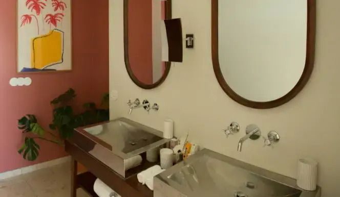 Hotelbadezimmer mit zwei modernen Waschbecken und eleganten Rundspiegeln