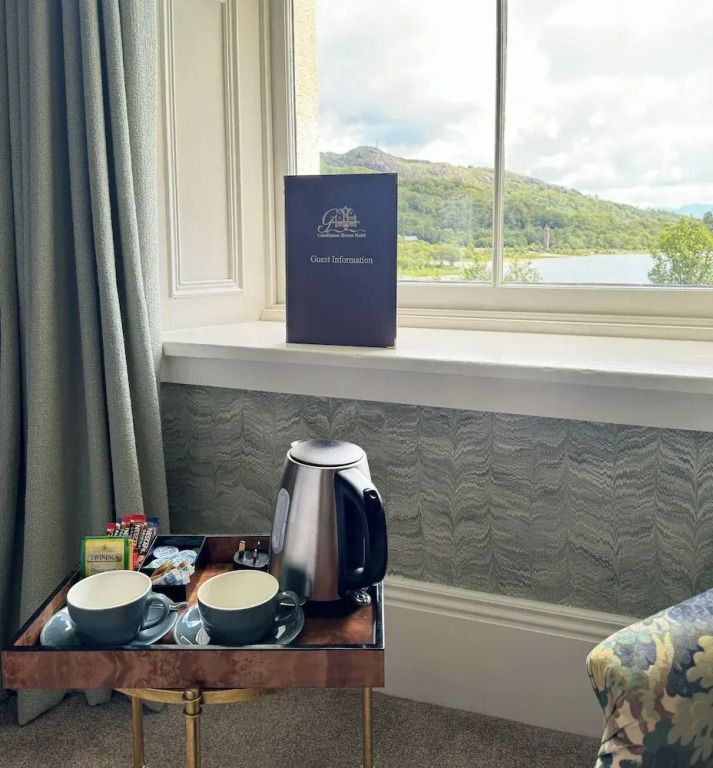 Tee-Setup mit Teekanne und Tassen vor einem großen Fenster mit Aussicht