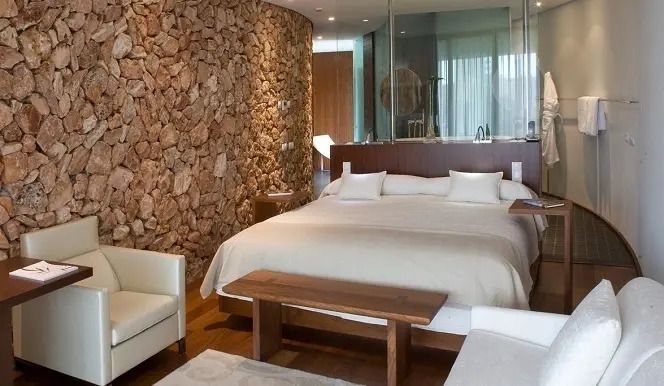 Modernes Hotelzimmer mit Natursteinwand und komfortablem Doppelbett
