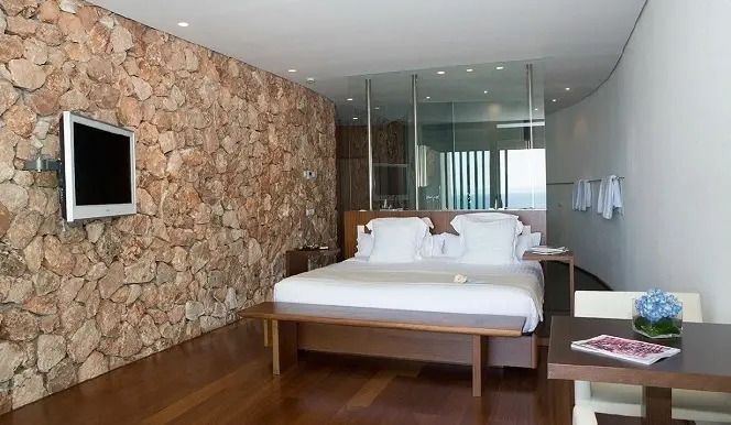 Modernes Hotelzimmer mit Steinwand und großen Fenstern