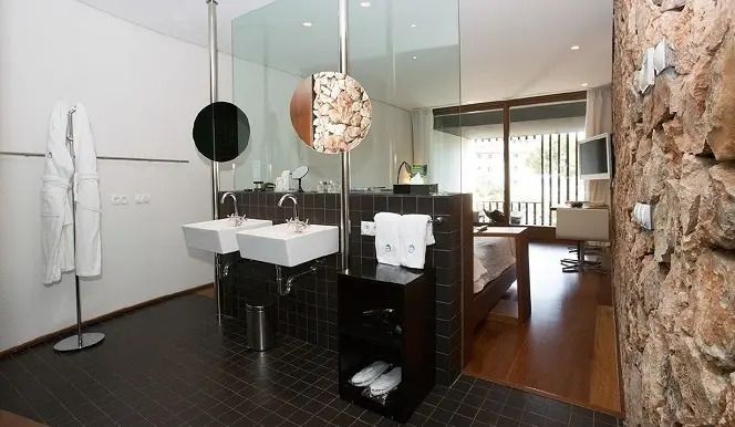 Offenes Badezimmer im Hotelzimmer mit zwei Waschbecken und Glaswänden
