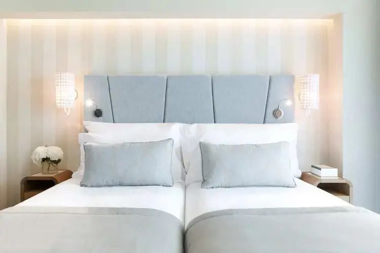 Modernes Doppelzimmer mit zwei eleganten Einzelbetten und sanfter Beleuchtung.