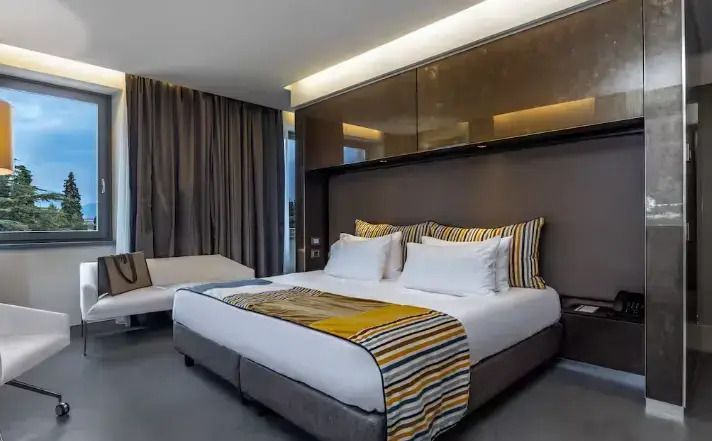 Deluxe Doppelbett im Zimmer mit eleganter Beleuchtung und Sitzbereich