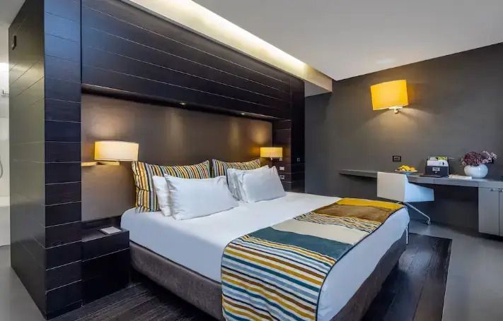Modernes Doppelzimmer mit stilvollen Beleuchtungselementen und gestreifter Bettdecke.