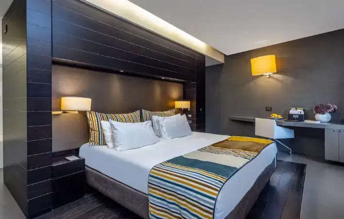 Modernes Doppelzimmer mit stilvoller Beleuchtung und gestreiften Kissen.