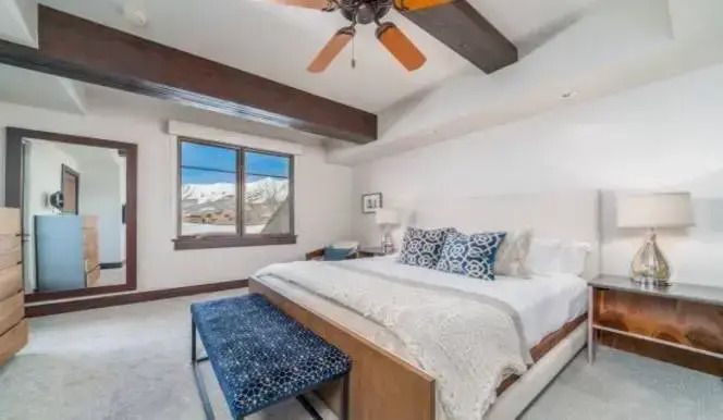Helles Schlafzimmer mit Holzbalken und einem großen Fenster mit Bergblick