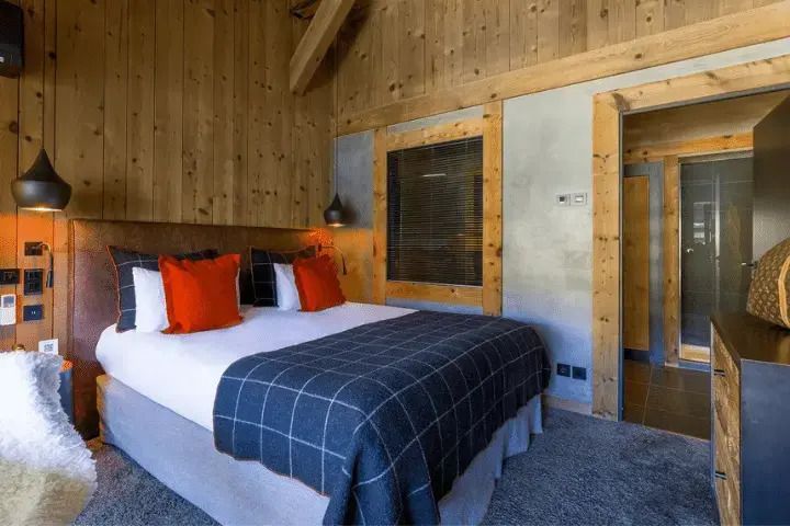 Gemütliches Schlafzimmer mit Doppelbett und Holzwänden in einem Chalet-Stil.