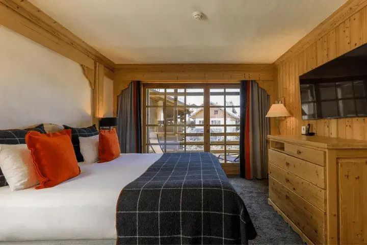 Gemütliches Schlafzimmer einer Junior-Suite mit großem Bett und Blick auf den Balkon