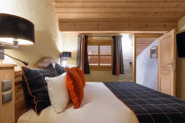 Schlafbereich einer Junior-Suite mit stylischer Beleuchtung und Holzdecke