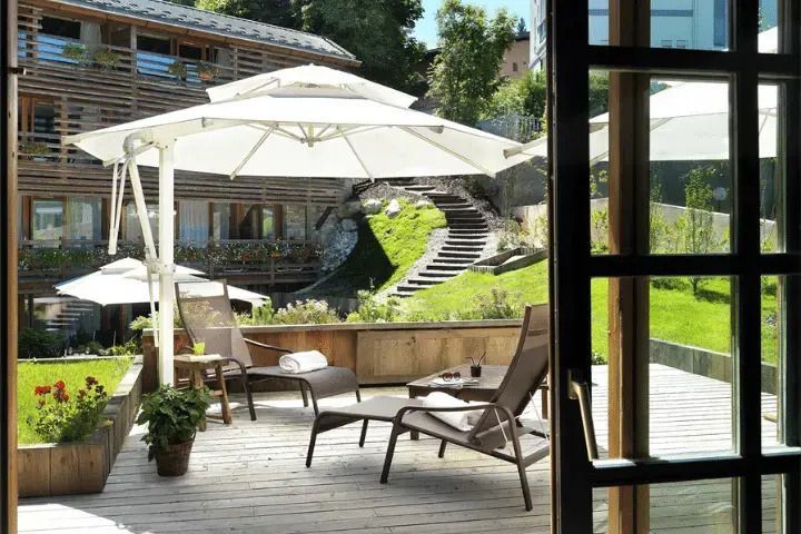 Terrasse mit Liegestühlen und Sonnenschirmen, Blick auf Garten und Natur