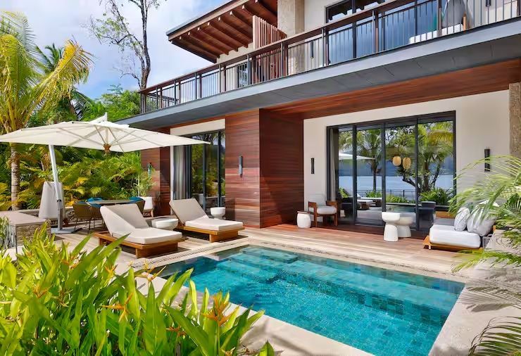 Private Terrasse mit Pool und Liegestühlen vor tropischer Kulisse