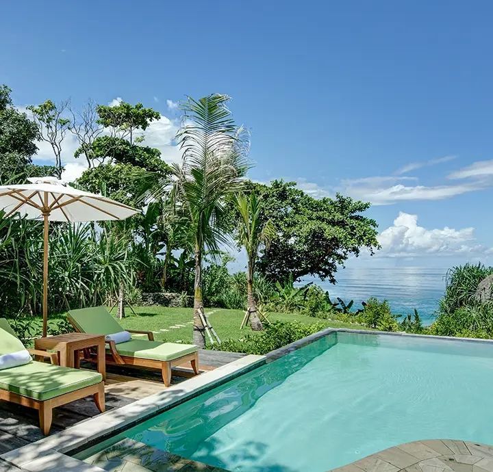 Privater Pool mit Liegestühlen und tropischer Gartenanlage