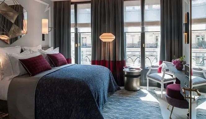 Elegantes Hotelzimmer mit großem Bett und Fenstern mit Vorhängen im Nolinski Paris.