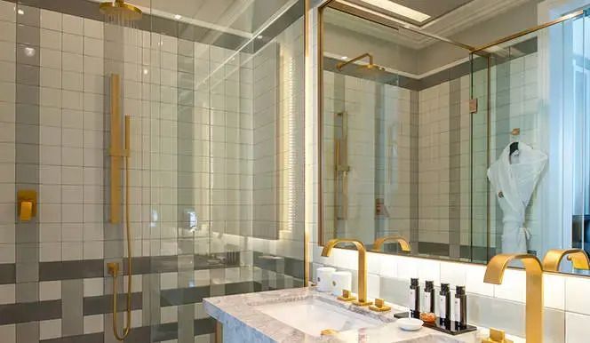 Modernes Badezimmer mit Dusche und goldenen Armaturen im Nolinski Paris.