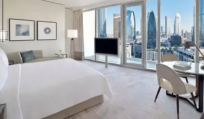 Modernes Hotelzimmer mit Blick auf Dubais Skyline und großem Doppelbett
