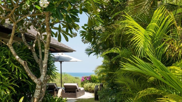Üppiger Gartenweg mit Blick auf das Meer und zwei Liegen in der Hilltop Pool Villa.