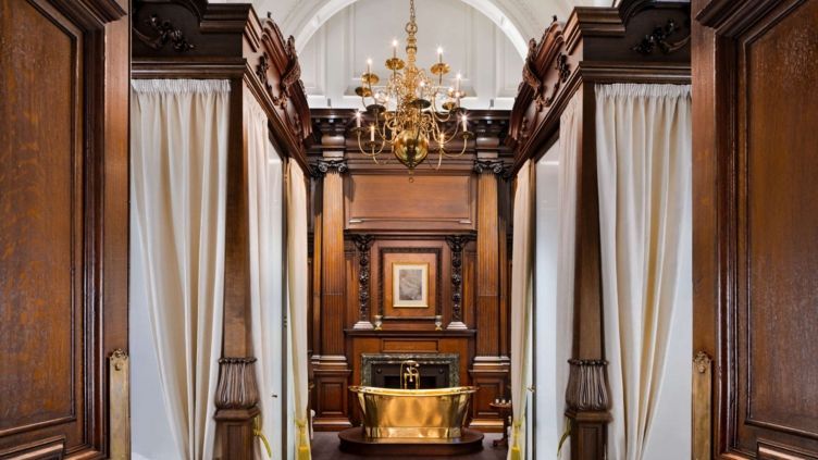 Badbereich mit goldenem Kamin und luxuriöser Badewanne in der Suite