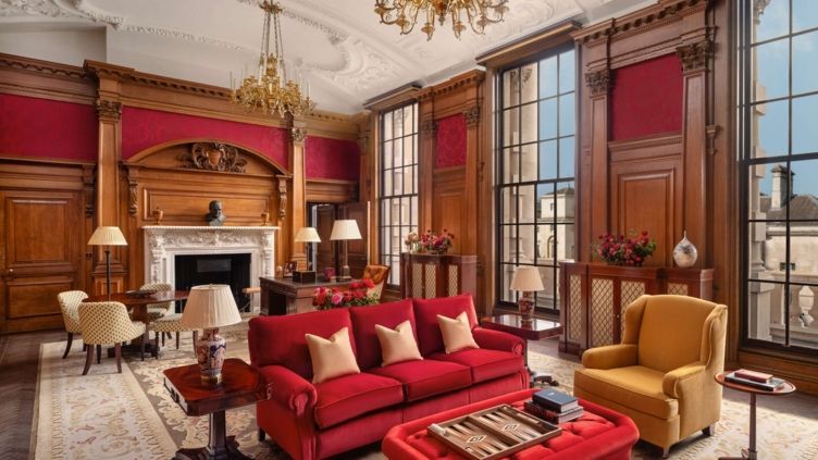 Prächtiges Wohnzimmer mit hohen Fenstern, roten Sofas und Kronleuchtern