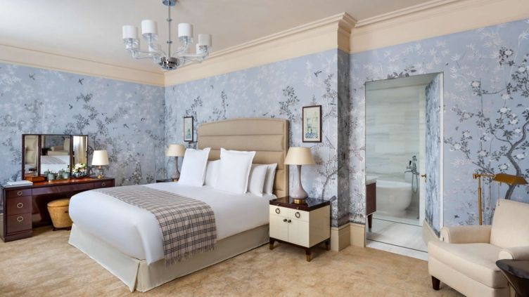 Luxuriöses Schlafzimmer mit beigem Doppelbett, eleganter Tapete und Badzugang.