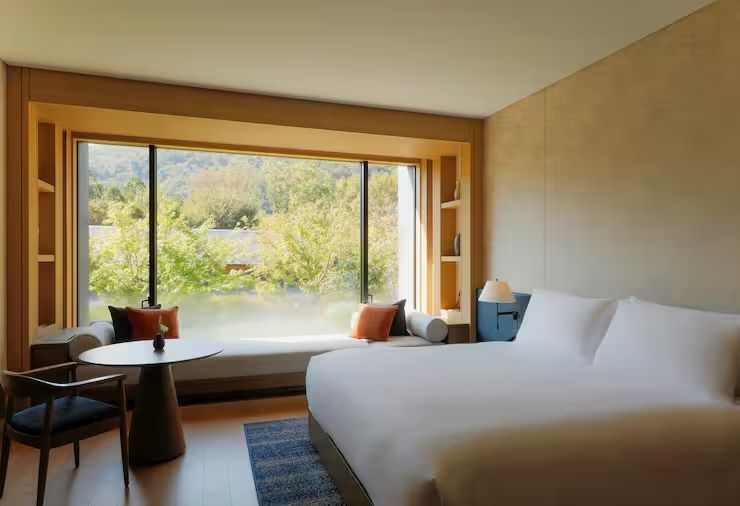 Geräumiges Hotelzimmer mit Doppelbett und Ausblick auf grüne Landschaft.