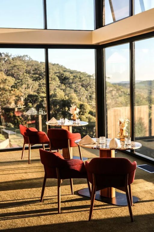 Restaurant mit Panoramablick auf Wald und Landschaft durch große Fenster.