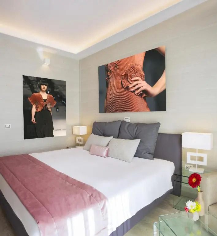 Schlafzimmer mit Kunstwerken und rosa Akzenten, modern gestaltet.