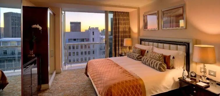 Geräumiges Schlafzimmer mit großem Bett und Stadtblick bei Sonnenuntergang
