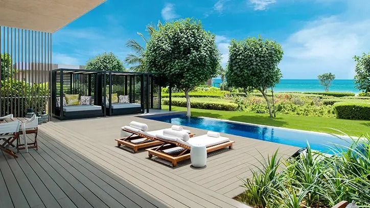 Private Terrasse mit Liegestühlen am Pool und Blick auf den Garten und das Meer