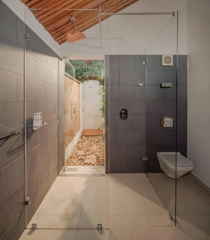 Moderne Badezimmerdusche mit Glaswänden und Natursteinakzenten