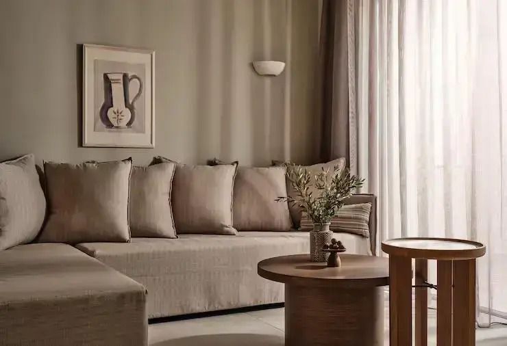 Elegante Suite-Lounge mit beiger Couch. Minimalistische Dekoration und große Fenster.