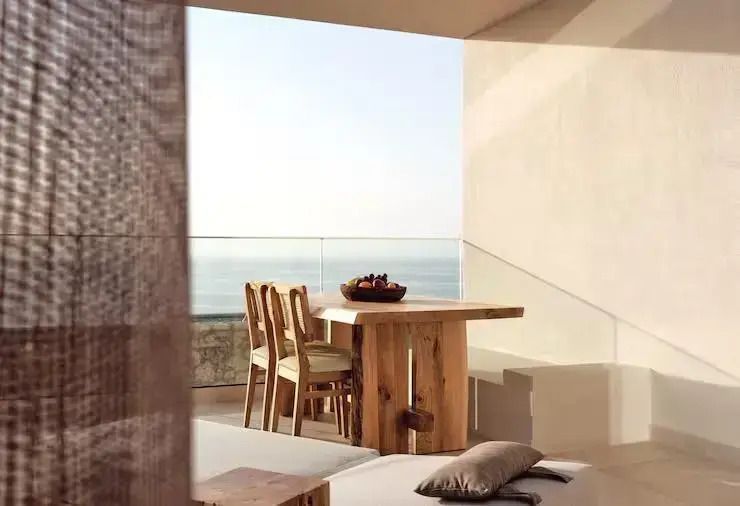 Holztisch mit Stühlen und Meerblick auf einer privaten Terrasse