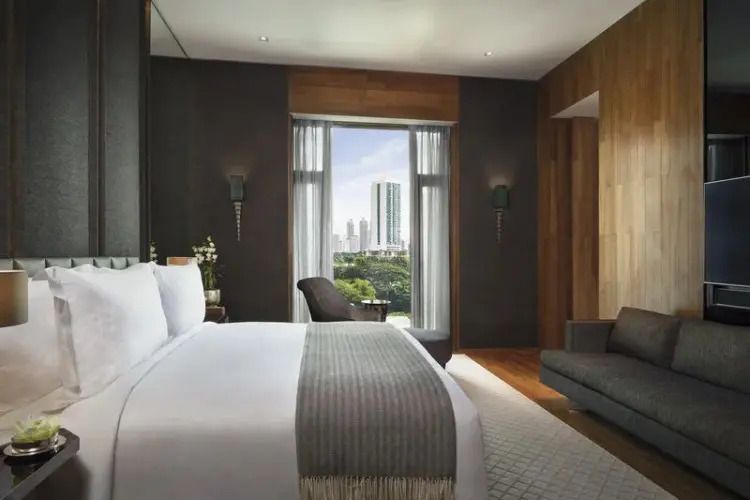 Elegant ausgestattete Suite mit großem Bett und Blick auf die Skyline von Bangkok.