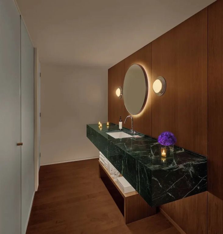 Modernes Badezimmer mit beleuchtetem Spiegel und stilvollem Waschbereich in Holzoptik