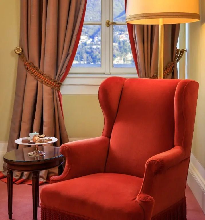 Roter Sessel vor Fenster mit Seeblick, dekorativer Beistelltisch