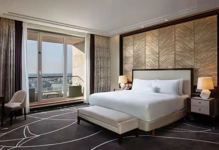 Luxuriöse Suite mit großem Bett und Balkon mit Stadtblick.