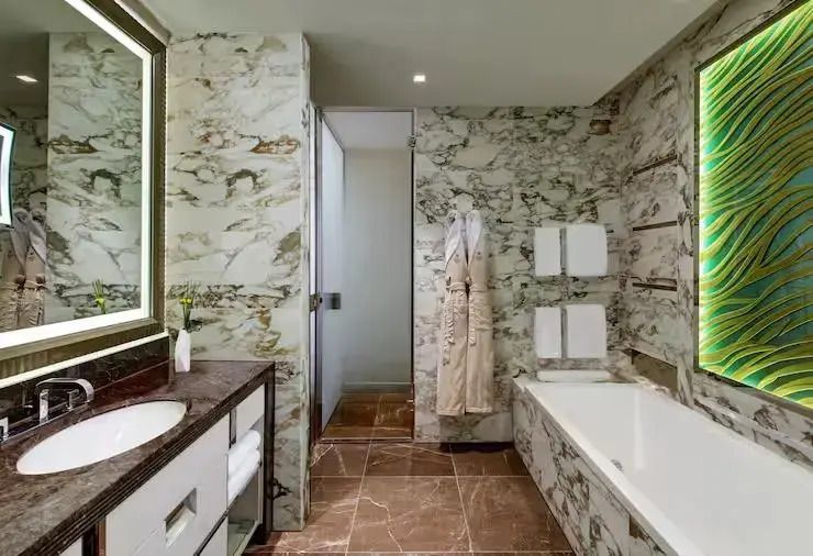 Marmorverkleidetes Badezimmer mit Badewanne und luxuriösen Annehmlichkeiten