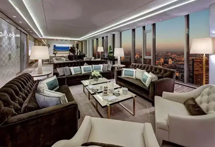 Großzügiger Loungebereich mit Sofas und Blick auf den Sonnenuntergang in der Presidential Suite