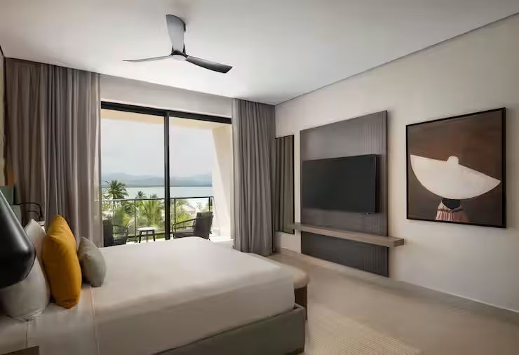 Helles Schlafzimmer mit Meerblick vom Balkon und einem großen TV