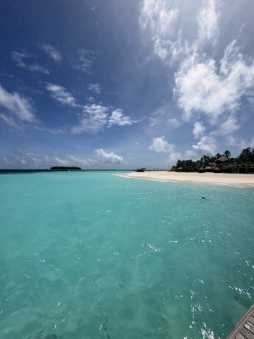 Türkise Lagune mit hellem Sandstrand vor der flach bewachsenen Insel Vabbinfaru unter Wolkenhimmel