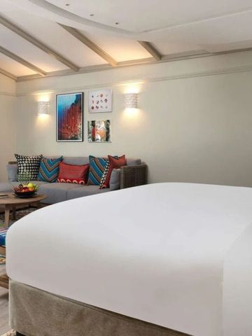 Geräumiges Zimmer mit gemütlicher Sitzecke, heller Bettwäsche und stilvoller Dekoration.